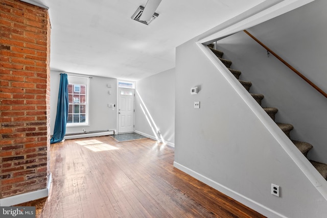 foyer featuring baseboards, visible vents, stairway, wood finished floors, and baseboard heating