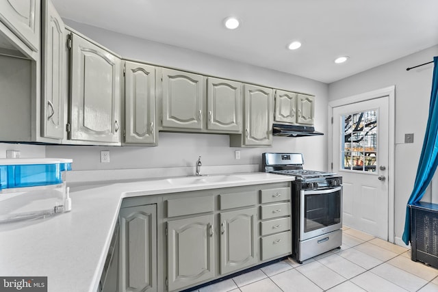 kitchen featuring stainless steel range with gas stovetop, light countertops, under cabinet range hood, a sink, and recessed lighting