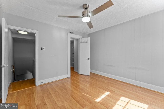 unfurnished bedroom with baseboards, visible vents, a ceiling fan, light wood-style flooring, and a textured ceiling