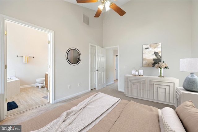 bedroom featuring light colored carpet, visible vents, a towering ceiling, connected bathroom, and baseboards