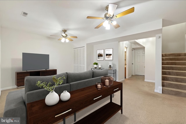 living room with light colored carpet, a ceiling fan, baseboards, stairs, and visible vents