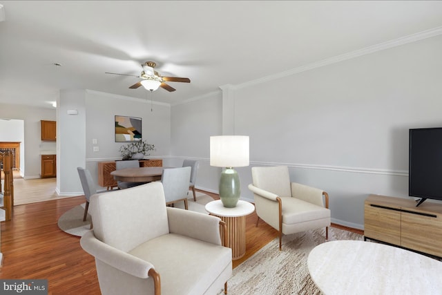 living area with ceiling fan, crown molding, baseboards, and wood finished floors