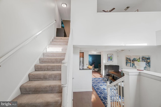 stairs featuring a high ceiling, baseboards, and wood finished floors