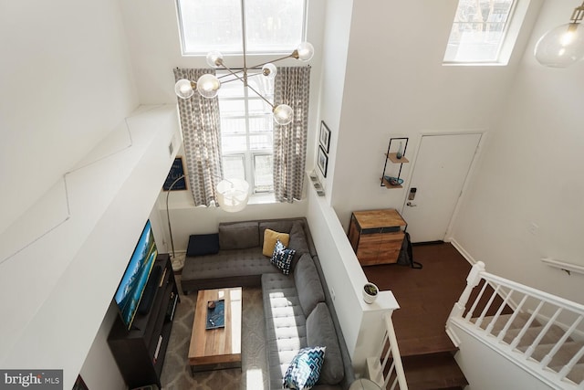 living area with a healthy amount of sunlight, a notable chandelier, a towering ceiling, and stairs