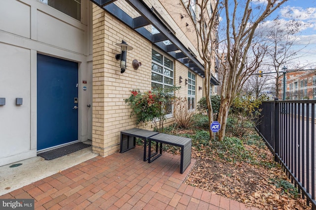 entrance to property featuring fence and brick siding