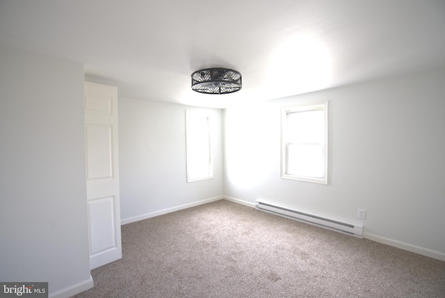 carpeted spare room featuring a baseboard heating unit, a healthy amount of sunlight, and baseboards