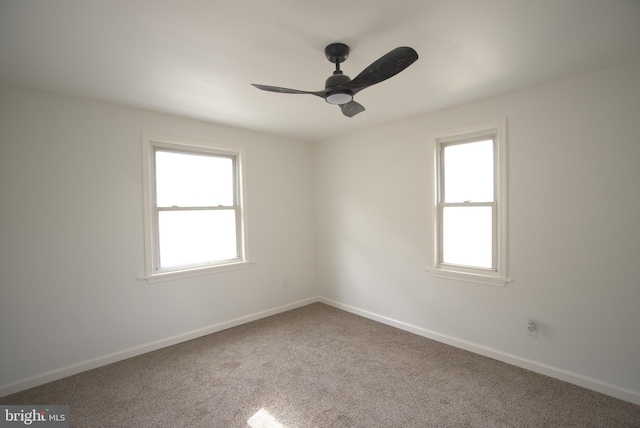 carpeted spare room featuring ceiling fan and baseboards