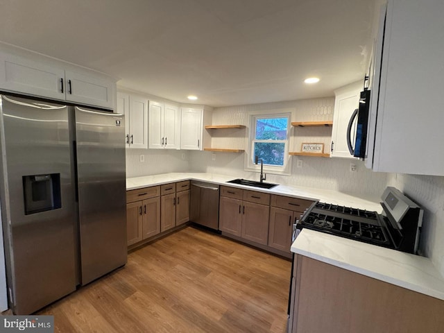 kitchen with open shelves, stainless steel appliances, recessed lighting, light wood-style flooring, and a sink