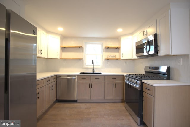 kitchen featuring a sink, stainless steel appliances, open shelves, and light countertops