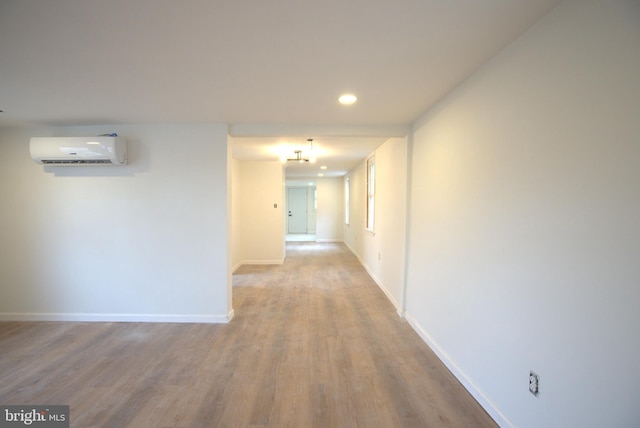 corridor with recessed lighting, an AC wall unit, baseboards, and wood finished floors