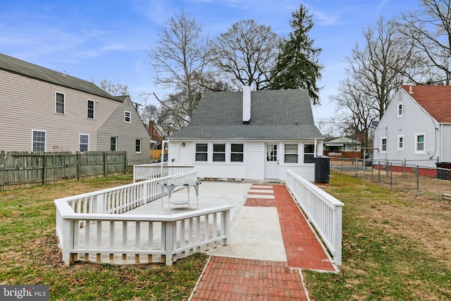 rear view of house featuring a shingled roof, a fenced backyard, a lawn, and a deck