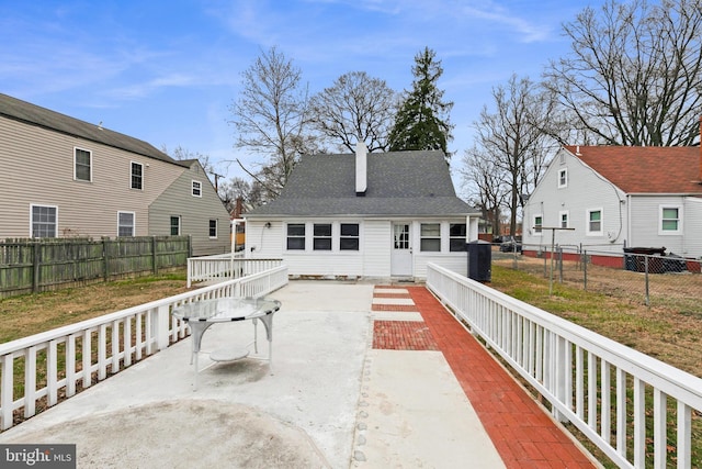 rear view of property featuring a fenced backyard, a patio, and roof with shingles