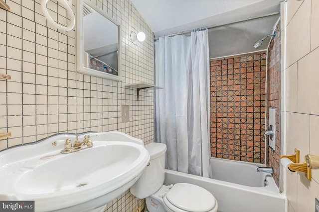 bathroom with toilet, a sink, tile walls, and shower / bathtub combination with curtain