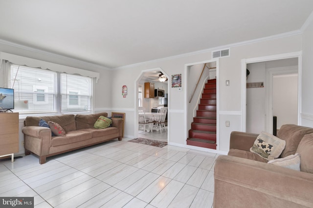 living area featuring ceiling fan, stairs, visible vents, and ornamental molding