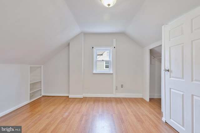 bonus room featuring built in shelves, baseboards, vaulted ceiling, and light wood finished floors