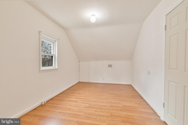 additional living space with vaulted ceiling, light wood finished floors, visible vents, and baseboards