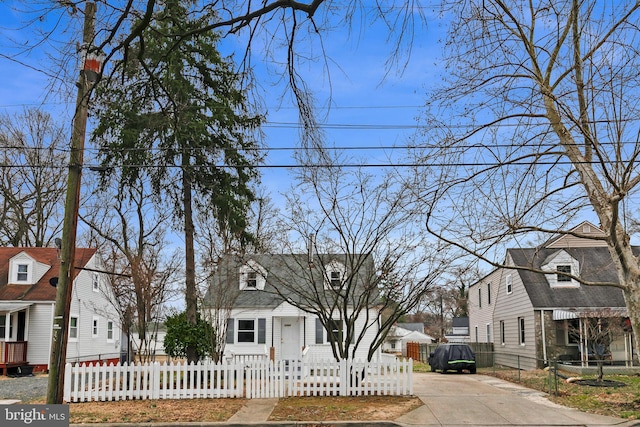 cape cod house with driveway, a fenced front yard, and a residential view