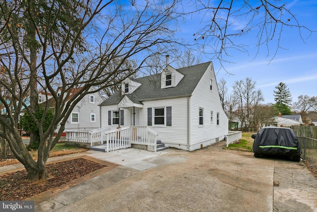 cape cod home featuring roof with shingles and fence