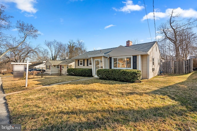 view of front of home with a chimney, a front lawn, and fence