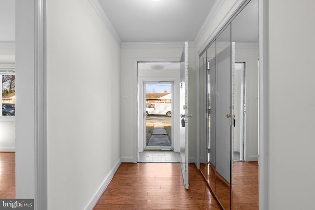 hallway with crown molding, wood finished floors, and baseboards