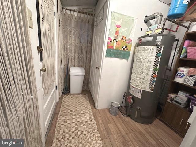 bathroom with toilet, wood finished floors, and water heater