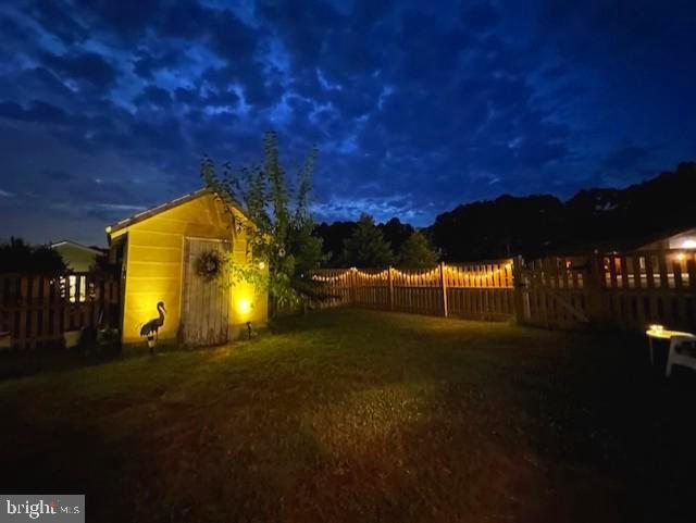 yard at night with an outbuilding, a storage unit, and a fenced backyard