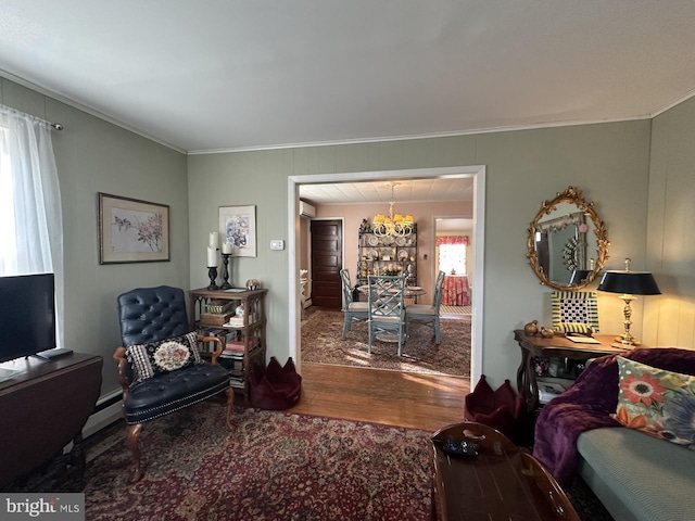 living area featuring ornamental molding, wood finished floors, a wall unit AC, a baseboard radiator, and a chandelier