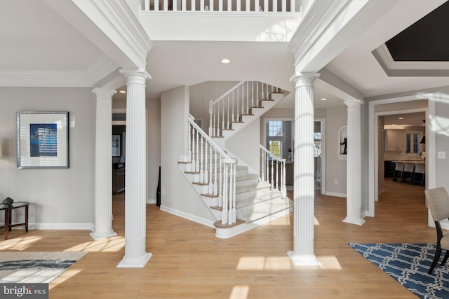 foyer with ornamental molding, decorative columns, baseboards, and wood finished floors