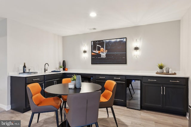 interior space with beverage cooler, light wood-type flooring, visible vents, and wet bar