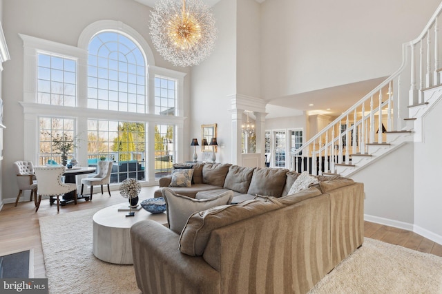 living area featuring a chandelier, stairway, baseboards, and wood finished floors