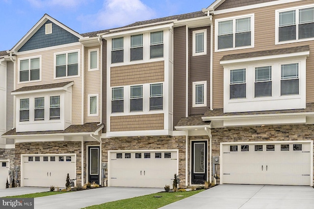 townhome / multi-family property featuring a garage, stone siding, and driveway