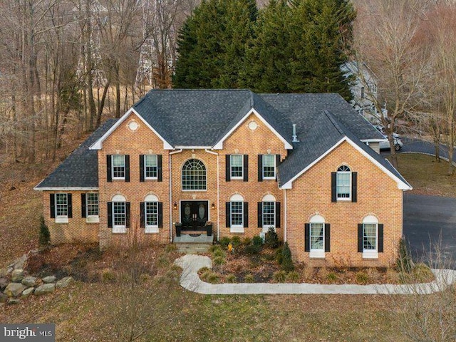 colonial inspired home with brick siding and roof with shingles