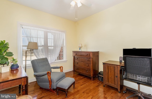 living area featuring a ceiling fan, baseboards, and wood finished floors