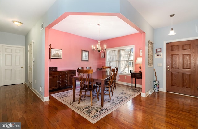 dining area featuring dark wood-style floors, a notable chandelier, visible vents, and baseboards