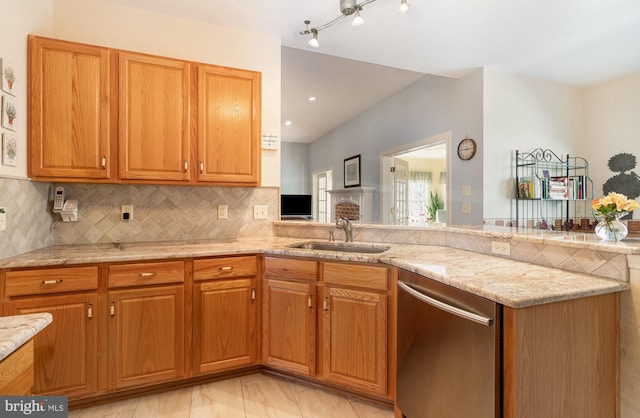 kitchen with light stone counters, a peninsula, a sink, decorative backsplash, and dishwasher