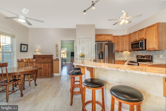 kitchen with appliances with stainless steel finishes, a breakfast bar, backsplash, and a wealth of natural light