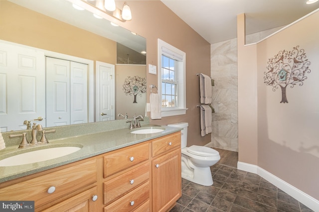 bathroom featuring a sink, a tile shower, and toilet