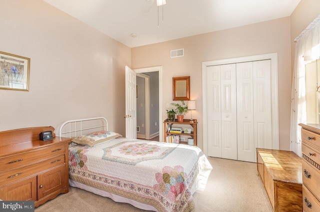 bedroom with ceiling fan, visible vents, a closet, and light colored carpet