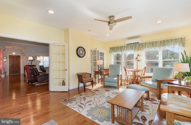 living area with recessed lighting, french doors, wood finished floors, and a wall mounted AC