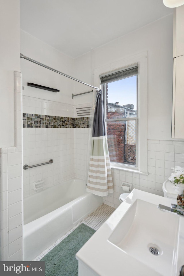 bathroom featuring shower / tub combo with curtain, a sink, and tile walls