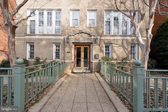 view of front of home featuring french doors, a fenced front yard, and brick siding