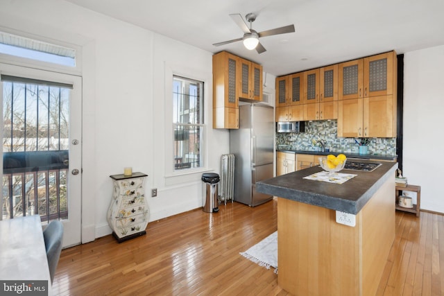 kitchen featuring glass insert cabinets, dark countertops, appliances with stainless steel finishes, and radiator heating unit