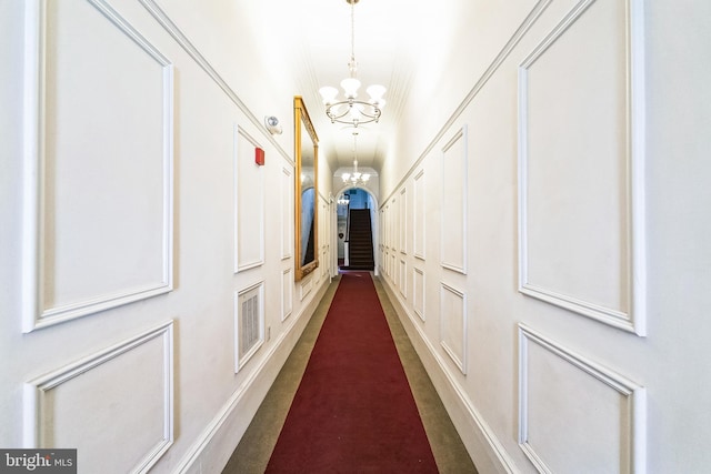 hallway with a decorative wall and a notable chandelier