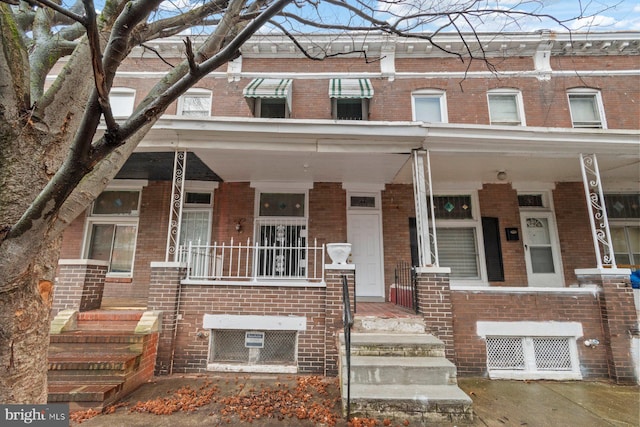 townhome / multi-family property with brick siding and a porch