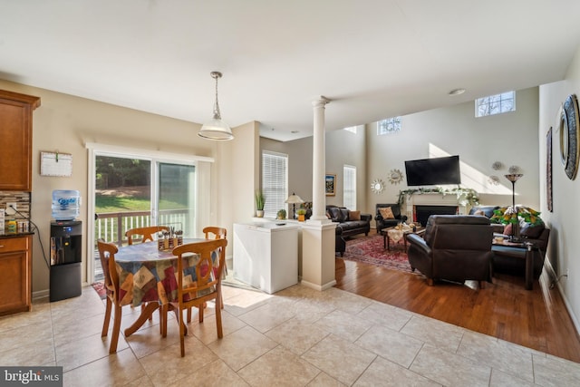 dining area featuring baseboards, a fireplace, light tile patterned flooring, and ornate columns