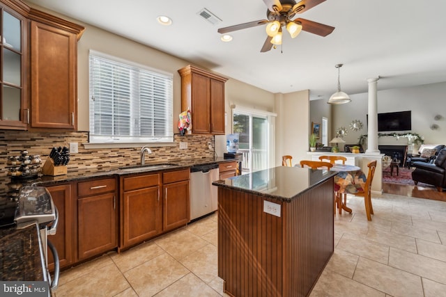 kitchen featuring glass insert cabinets, brown cabinets, decorative light fixtures, stainless steel appliances, and a sink