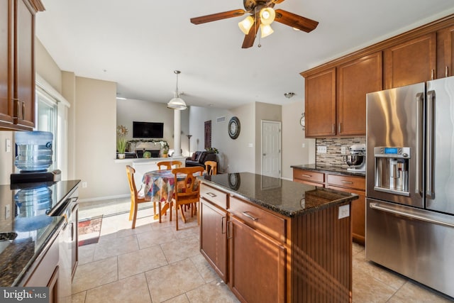 kitchen with open floor plan, high end fridge, light tile patterned floors, and decorative backsplash