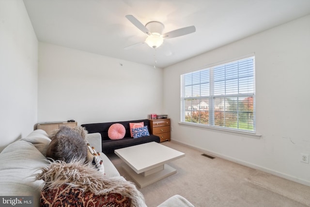 living area with a ceiling fan, light colored carpet, visible vents, and baseboards