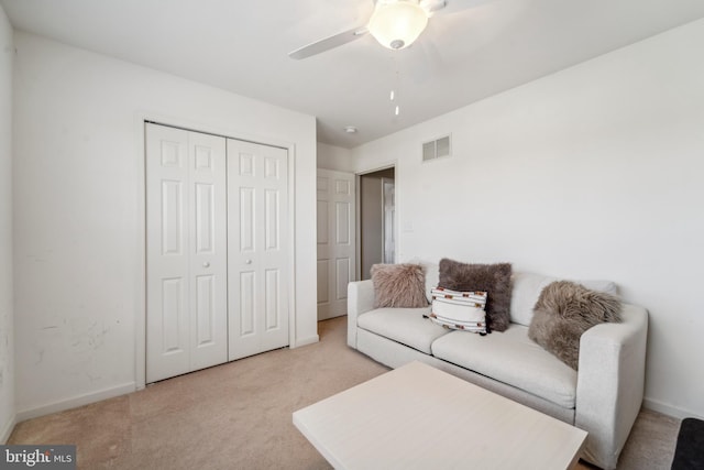 living area featuring a ceiling fan, visible vents, light carpet, and baseboards