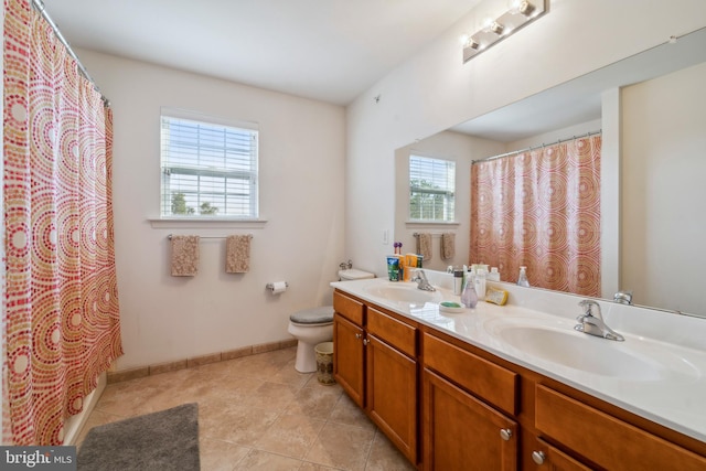 full bath with double vanity, tile patterned flooring, a sink, and baseboards